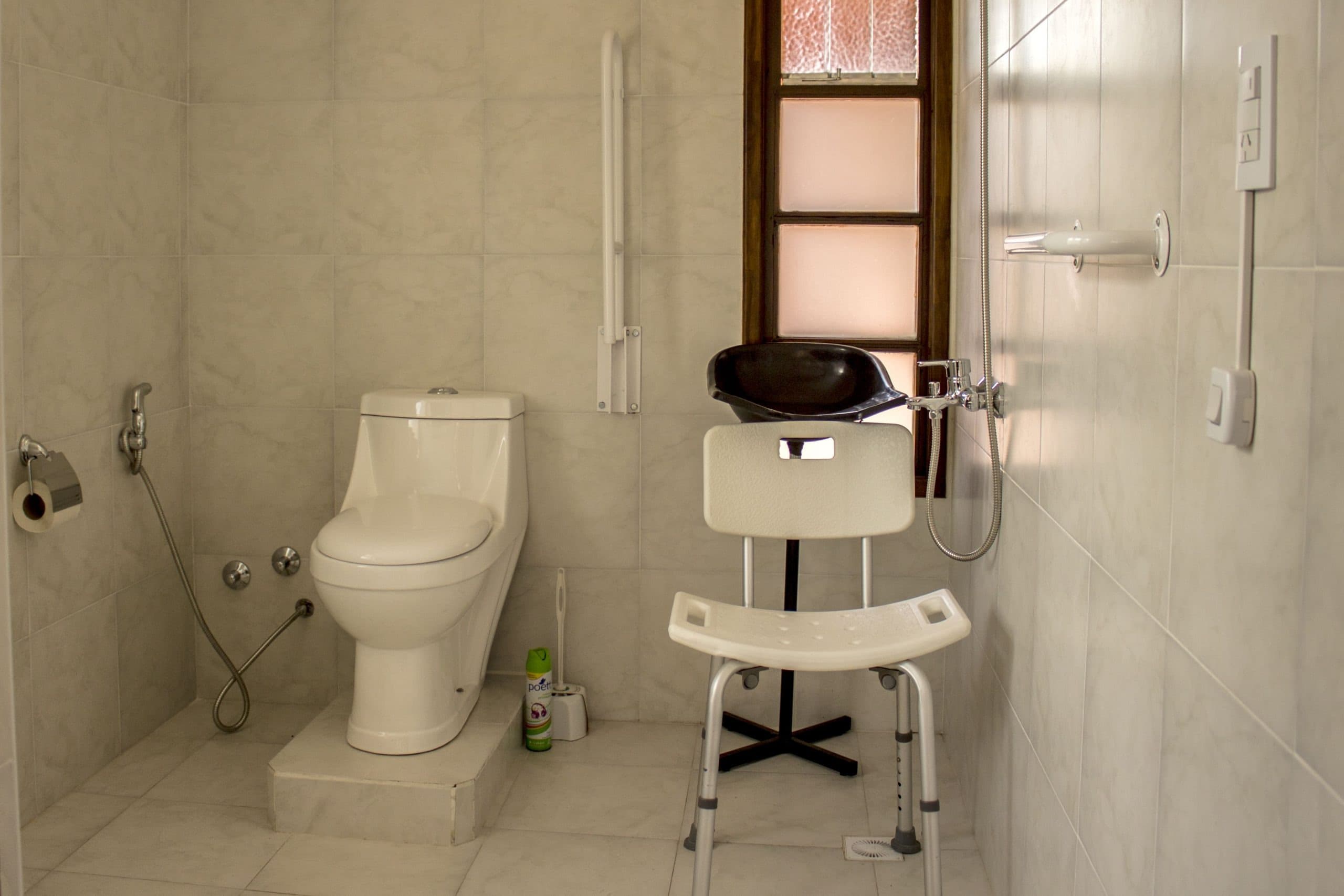 Baño adaptado con barrales y silla de ducha