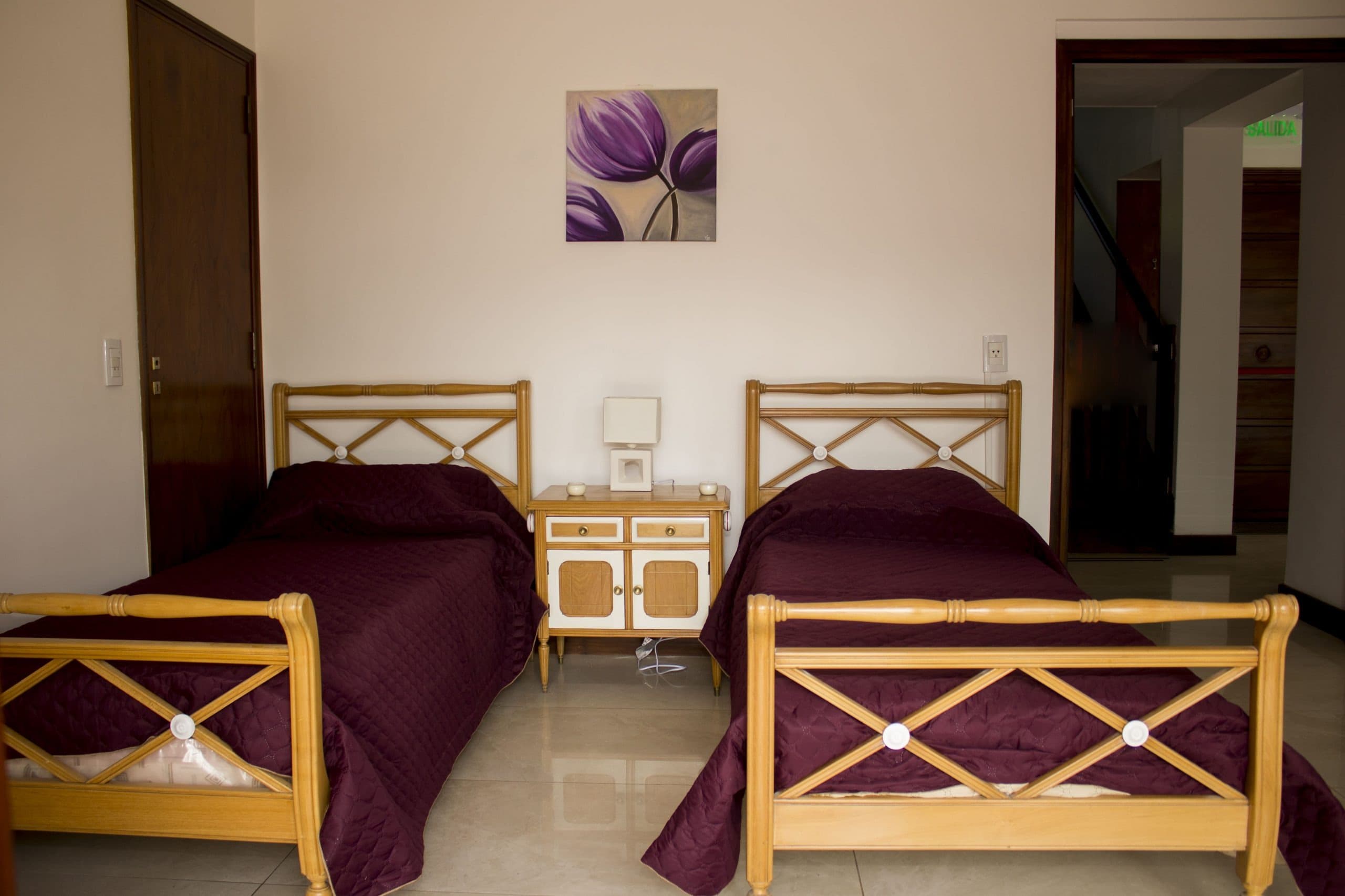 Habitación con dos camas y cubrecamas bordó