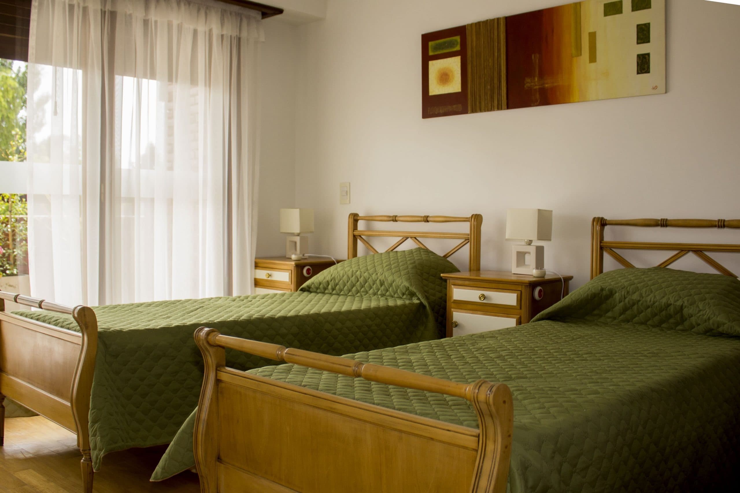 Habitación luminosa con dos camas y cubrecamas verde