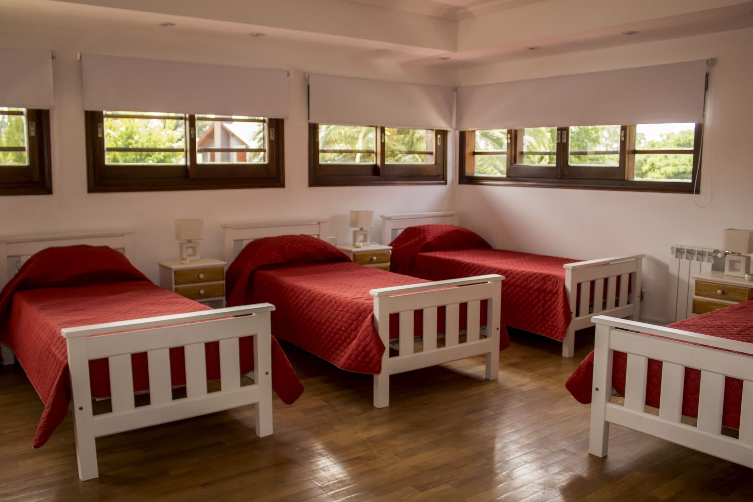 Habitación compartida con varias camas y cubrecamas rojo